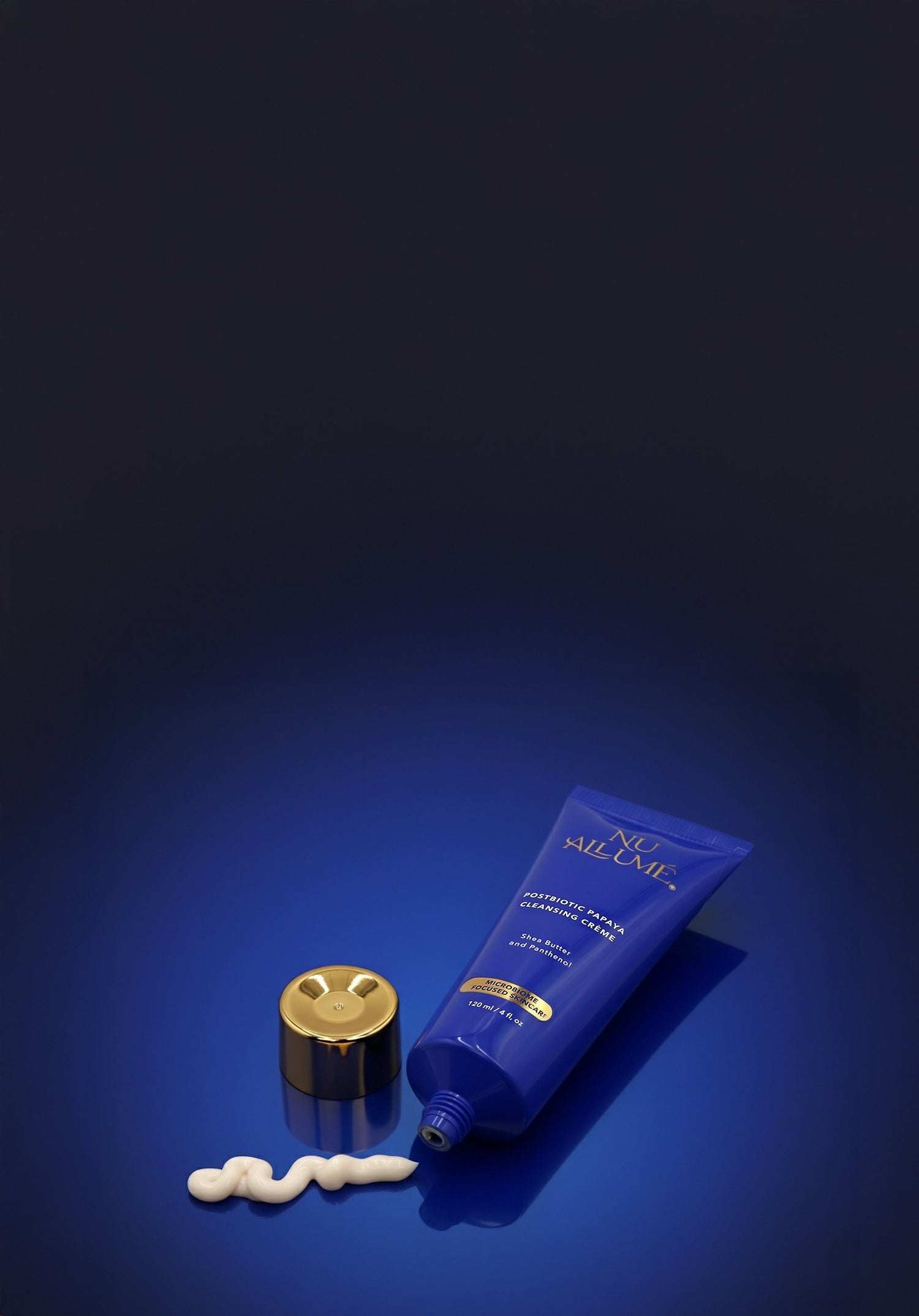 Tube of Postbiotic Papaya Cleanser with white cream on a dark blue background