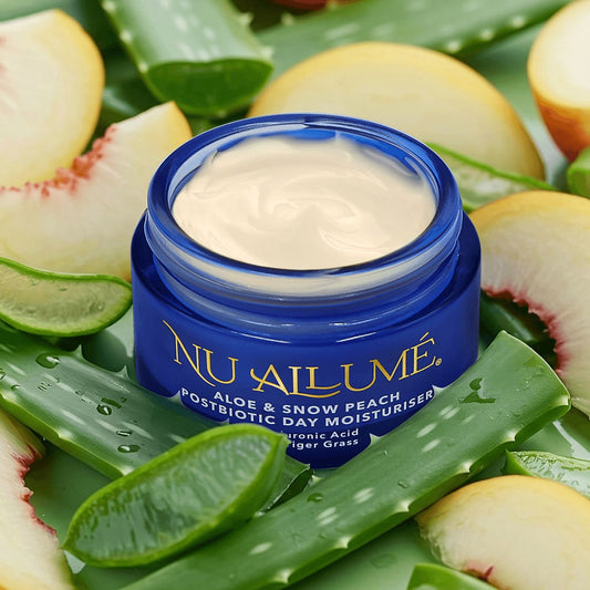 Jar of Nu Allume aloe and snow peach moisturizer surrounded by aloe vera leaves and peaches.