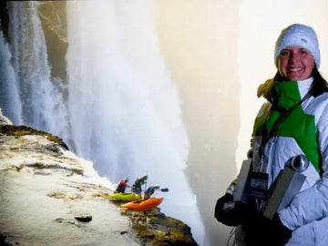 Desre in winter clothing standing in front of her winning photo of a waterfall with kayakers below.