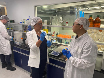 Desre talking to a microbiome scientist in a laboratory setting with equipment.