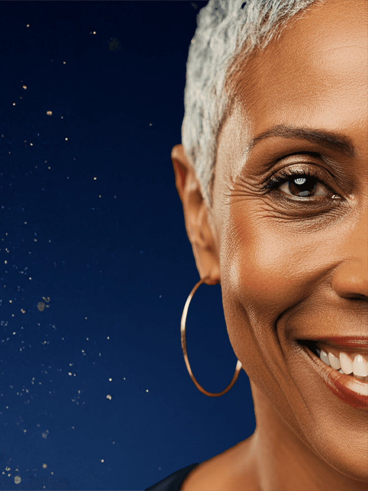 A background photo of gold flecks flying through the air like dust towards one half of the face of a middle aged woman smiling.