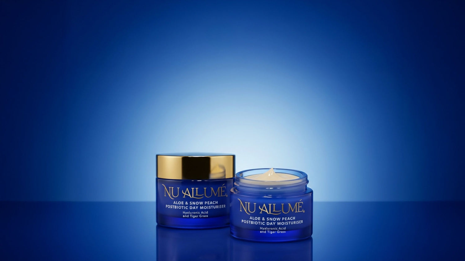 Two jars of Nu Allume Aloe and Snow Peach Postbiotic Day Moisturiser on a blue background.