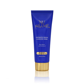 Tube of Nu Allume Postbiotic Papaya Cleansing Crème with gold cap and reflecting below off a white shiny surface