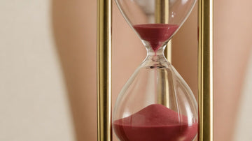 Hourglass with red sand on a beige background