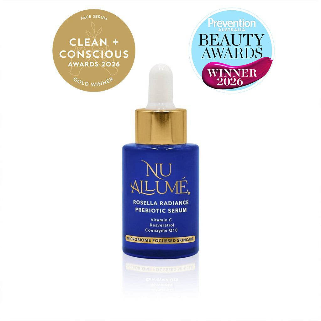 A blue dropper bottle of Nu Allume Rosella Radiance Prebiotic Serum with a gold cap, shown on a white background with two award badges at the top: a gold 'Clean + Conscious Awards 2026 Gold Winner' seal and a blue and magenta 'Prevention Beauty Awards Winner 2026' badge.